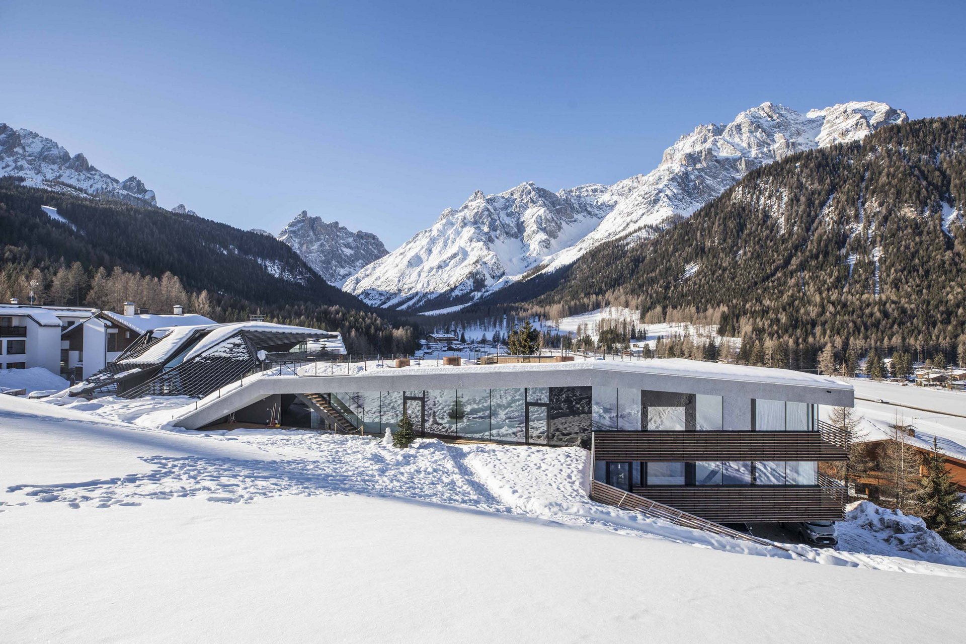 Urlaub mit Stil in der Residence Alma Paramout Modernes Haus im Schnee mit Blick auf schneebedeckte Berge und Wald