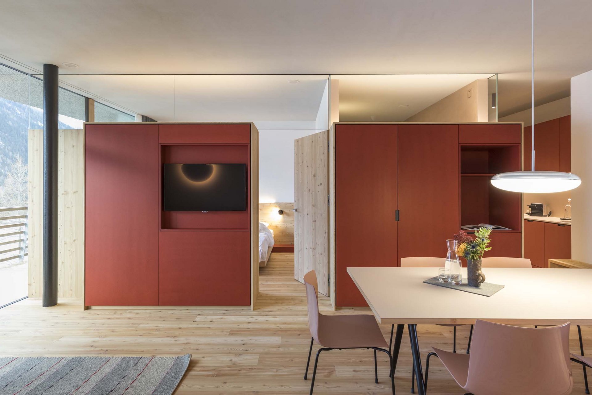 Urlaub mit Stil in der Residence Alma Paramout Modernes Apartment mit Holzfußboden, rotem Schrank und großem Fenster mit Bergblick