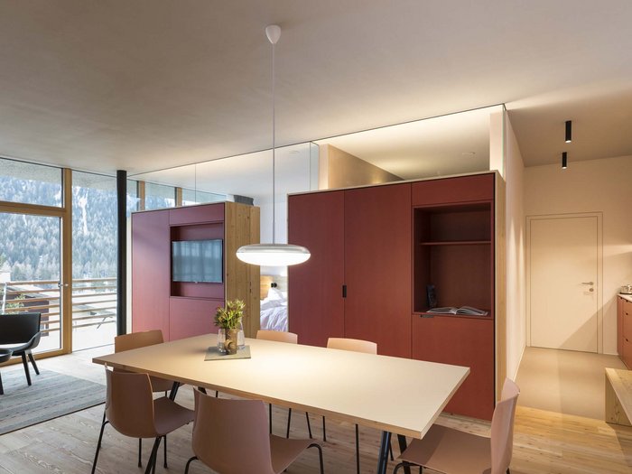 Urlaub mit Stil in der Residence Alma Paramout Moderner Essbereich mit hellen Stühlen, Tischen und rotem Schrank nahe Fenster und Balkon