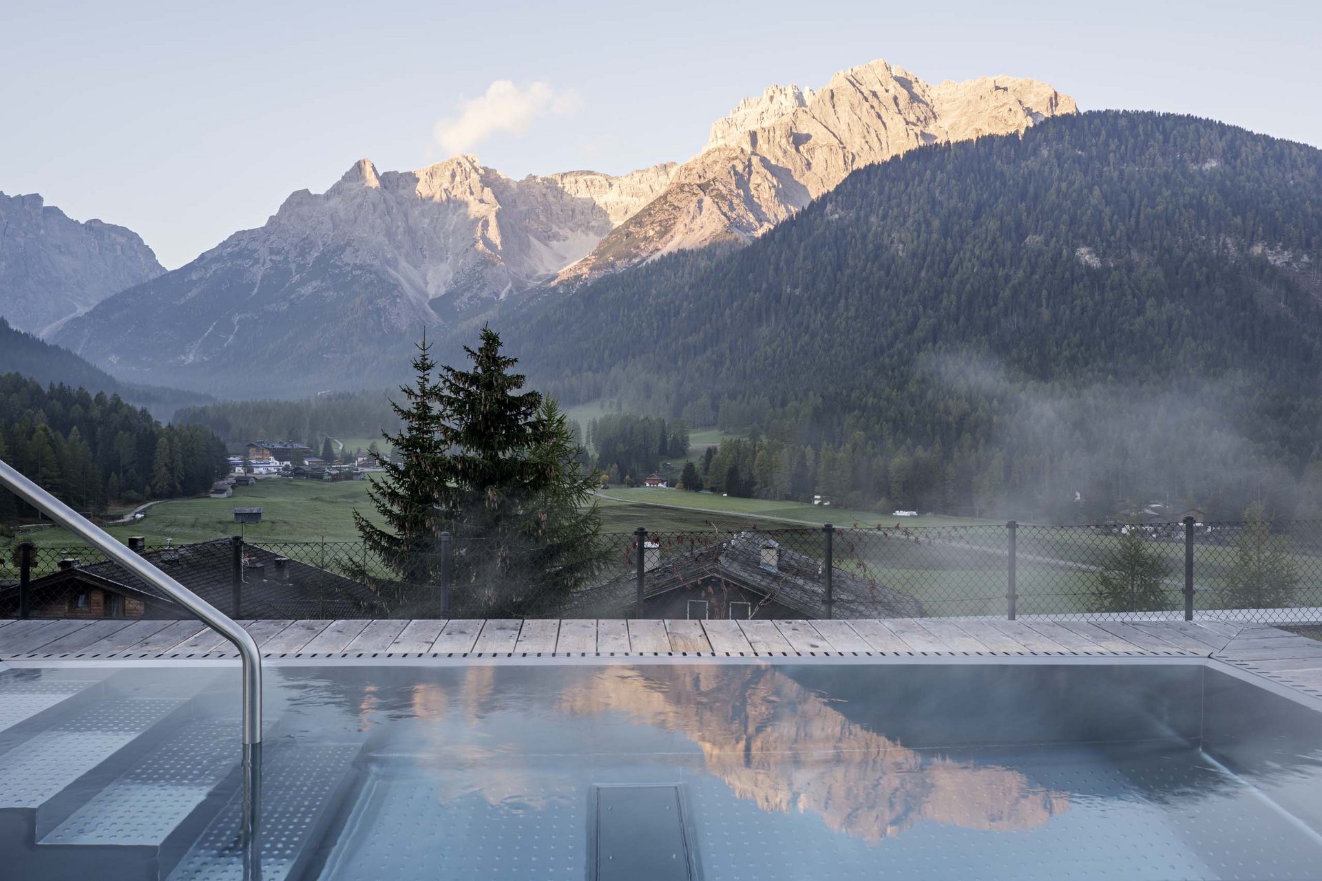 Urlaub mit Stil in der Residence Alma Paramout Dampfender Pool mit Bergpanorama in den Dolomiten bei Sonnenaufgang