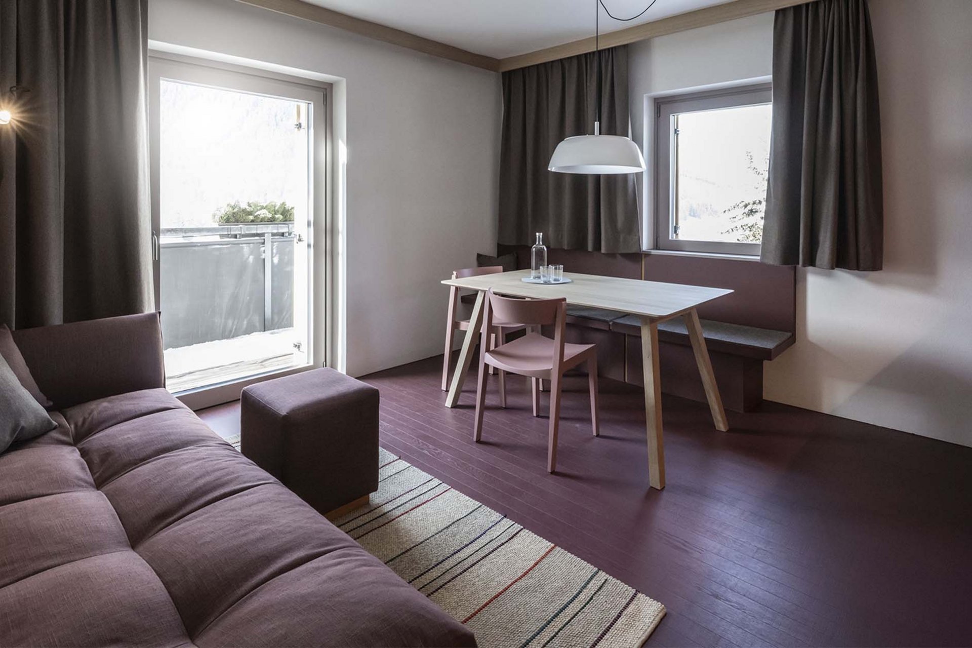 Urlaub mit Stil in der Residence Alma Paramout Modernes Wohnzimmer mit Couch, Esstisch und Fenster mit Vorhängen