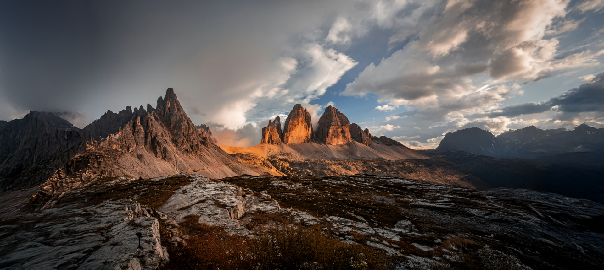 Get to know us! Sunset over jagged Dolomite peaks under dramatic cloudy sky