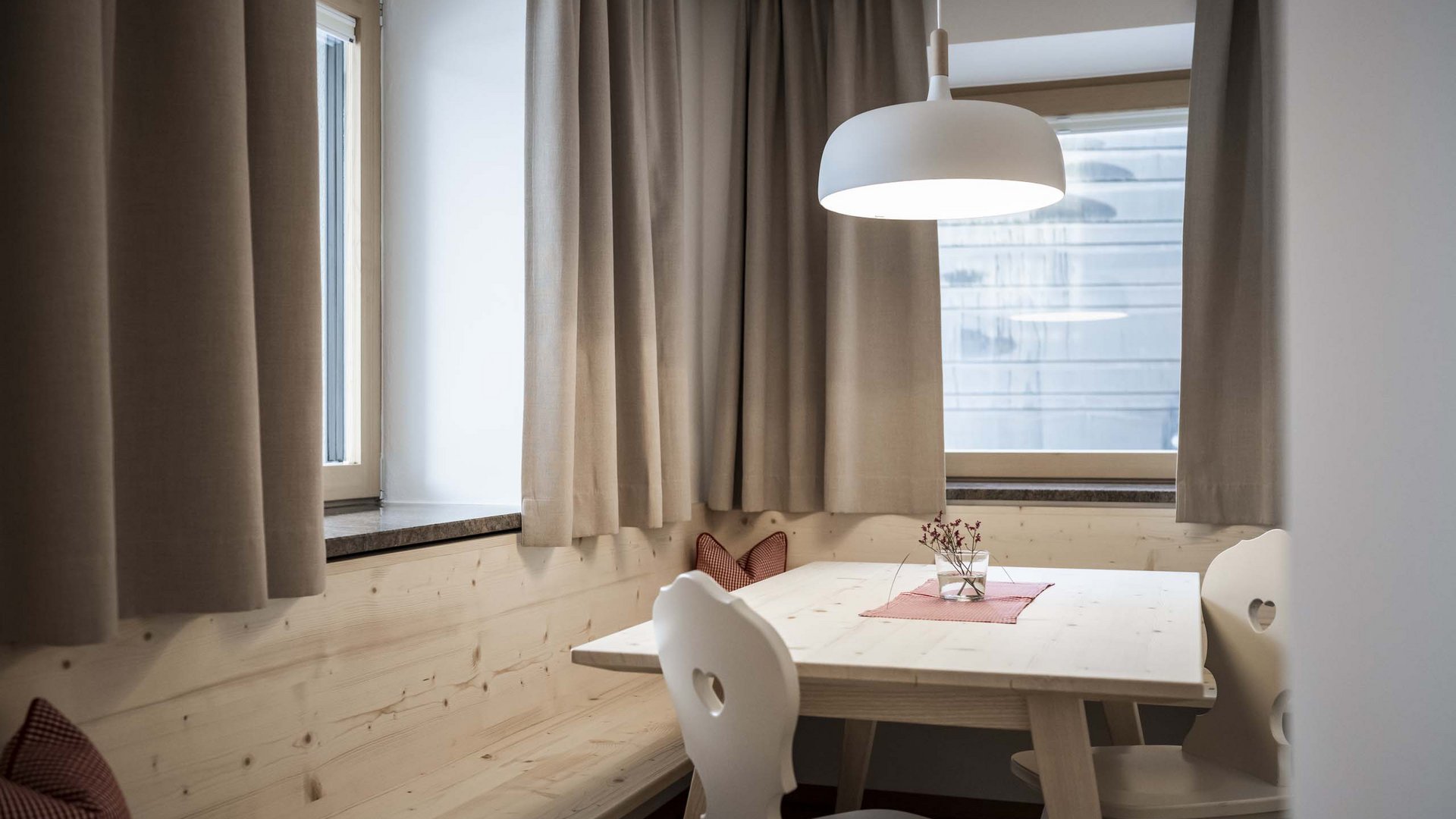 Residence Villa Rainer Accogliente zona pranzo con tavolo in legno, sedie, panca e lampada a sospensione