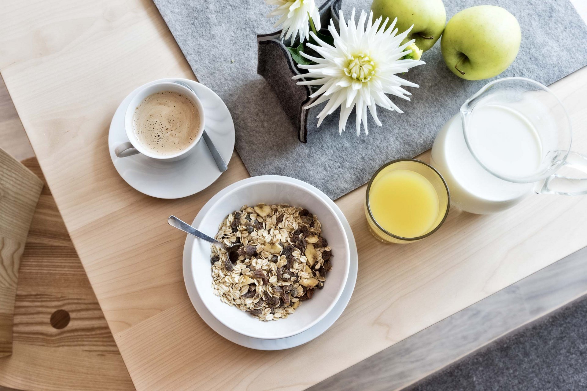 Naturerlebnis in der Villa Rainer Frühstückstisch mit Müsli, Kaffee, Saft, Milch, grünen Äpfeln und Blume