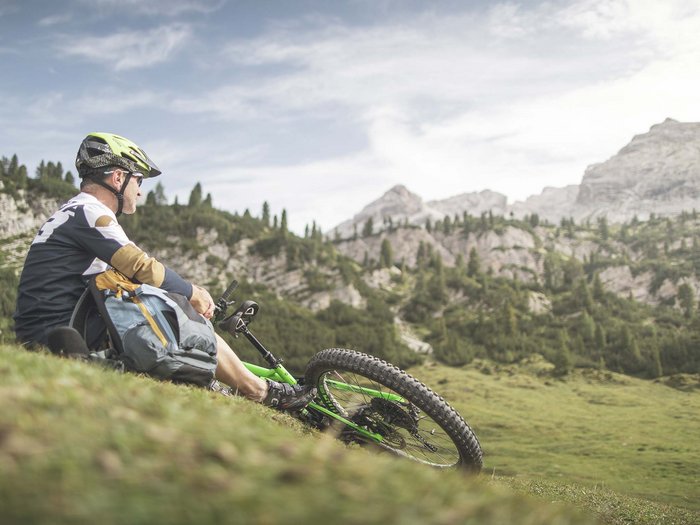 La località perfetta per la mtb: Sesto Ciclista in mountain bike seduto su un prato con vista sulle montagne boschive