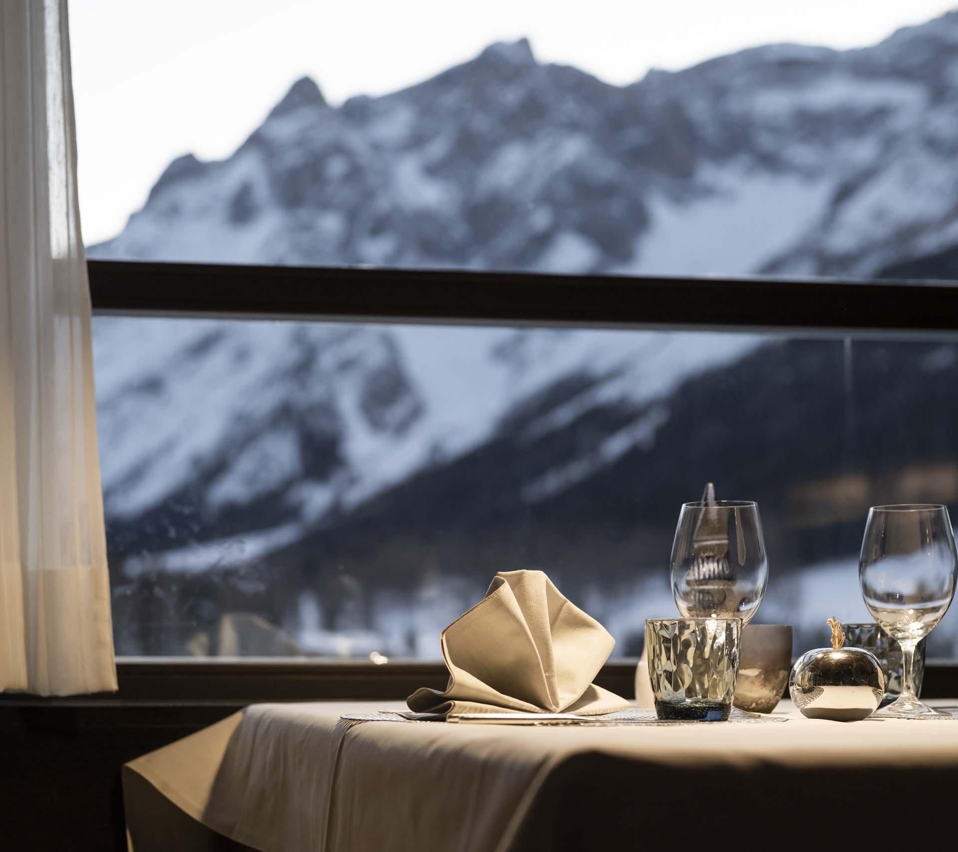 Property detail page - Hotel Rainer Elegant table setting with snowy mountain view through a window