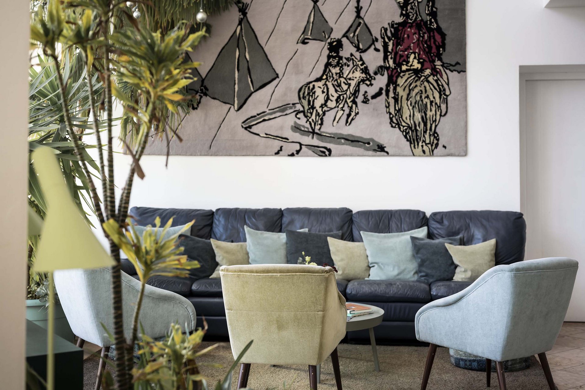 The Residence Königswarte Strata Cozy living room with sofa, armchairs, and western-themed wall tapestry