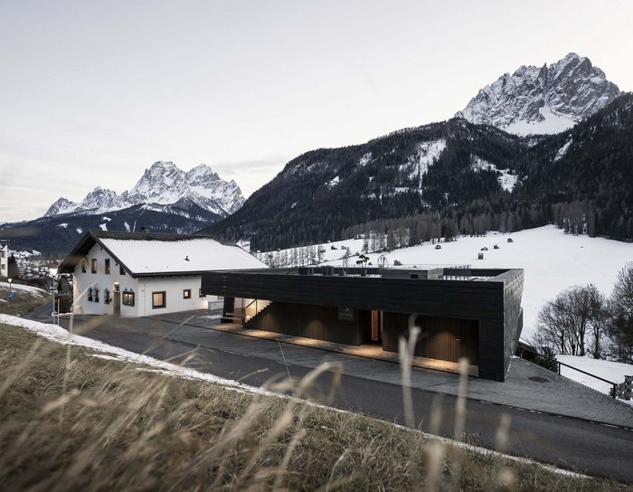 Ihr Familienresort in Südtirol Schnee bedeckte Berge und Häuser mit Blick auf die Dolomiten bei Dämmerung
