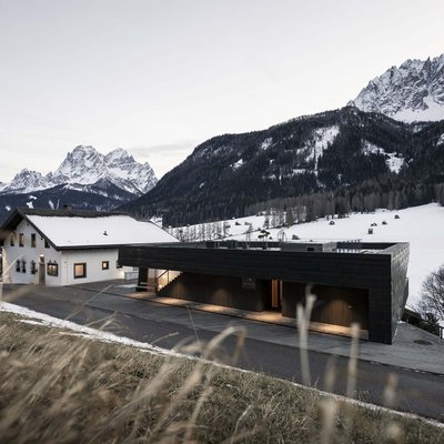 Ihr Familienresort in Südtirol Schnee bedeckte Berge und Häuser mit Blick auf die Dolomiten bei Dämmerung
