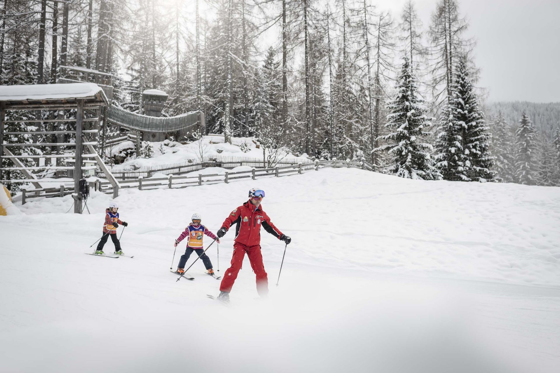The in-house Rainer Ski School Ski instructor teaching two children to ski in a snowy forest