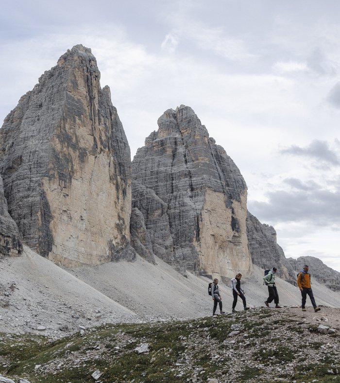 Zwei Wanderer sitzen auf Felsen mit Blick auf die Dolomiten und bewölkten Himmel