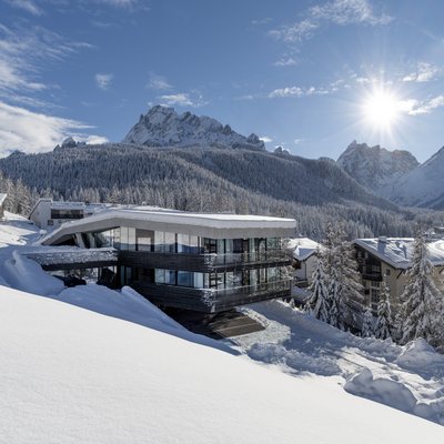 Modernes Haus im Schnee mit Blick auf schneebedeckte Berge und Wald