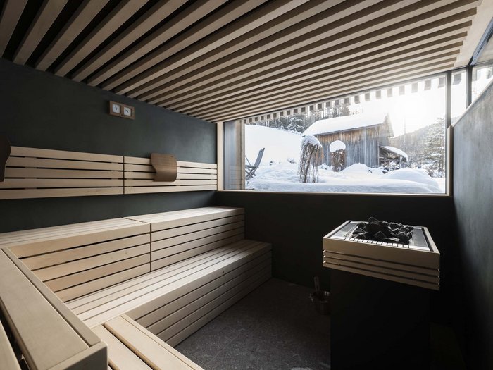 The Residence Königswarte Strata Modern sauna interior with wooden bench and snowy cabin view outside