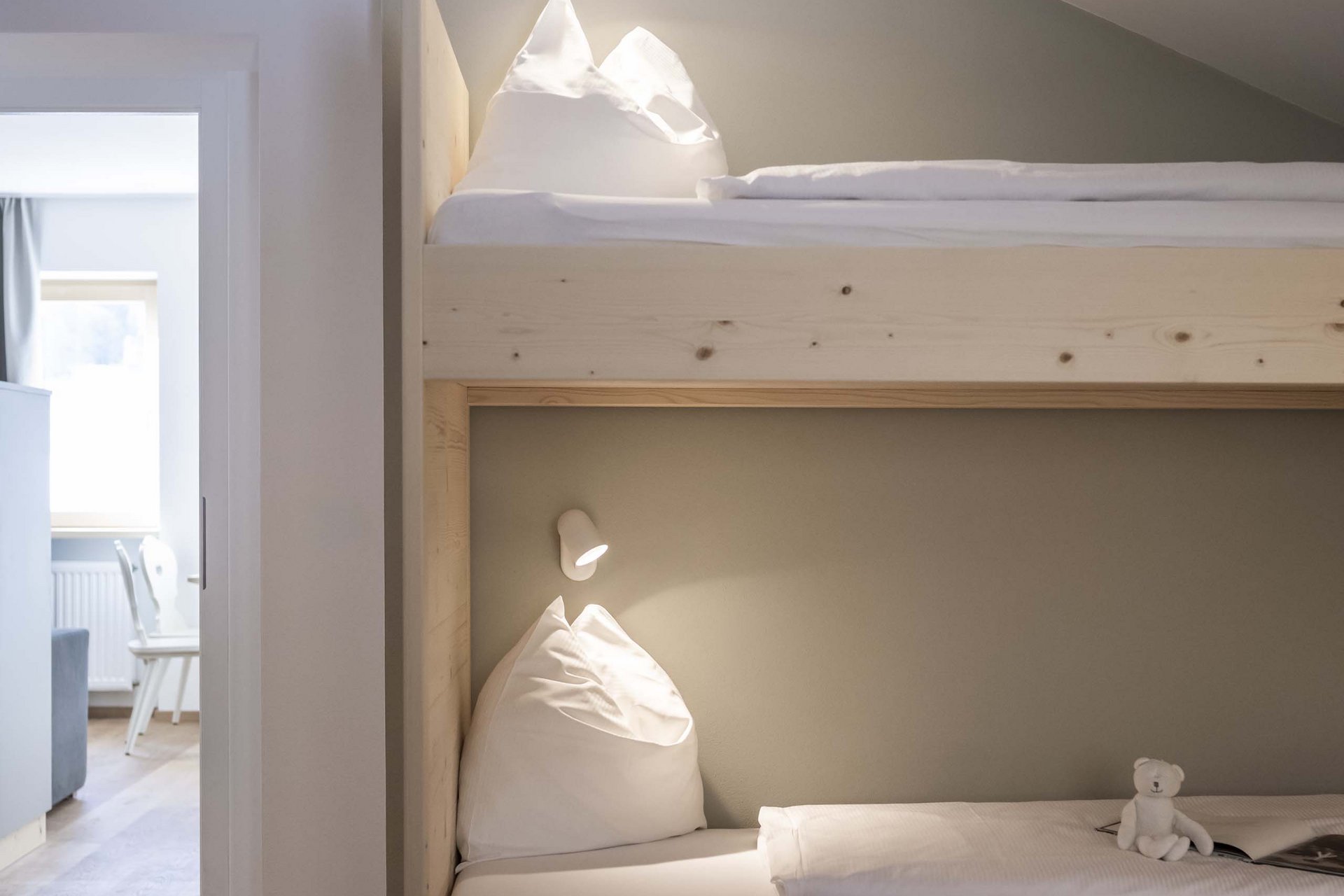 Naturerlebnis in der Villa Rainer Etagenbett aus hellem Holz mit weißer Bettwäsche und kleinem Teddybär