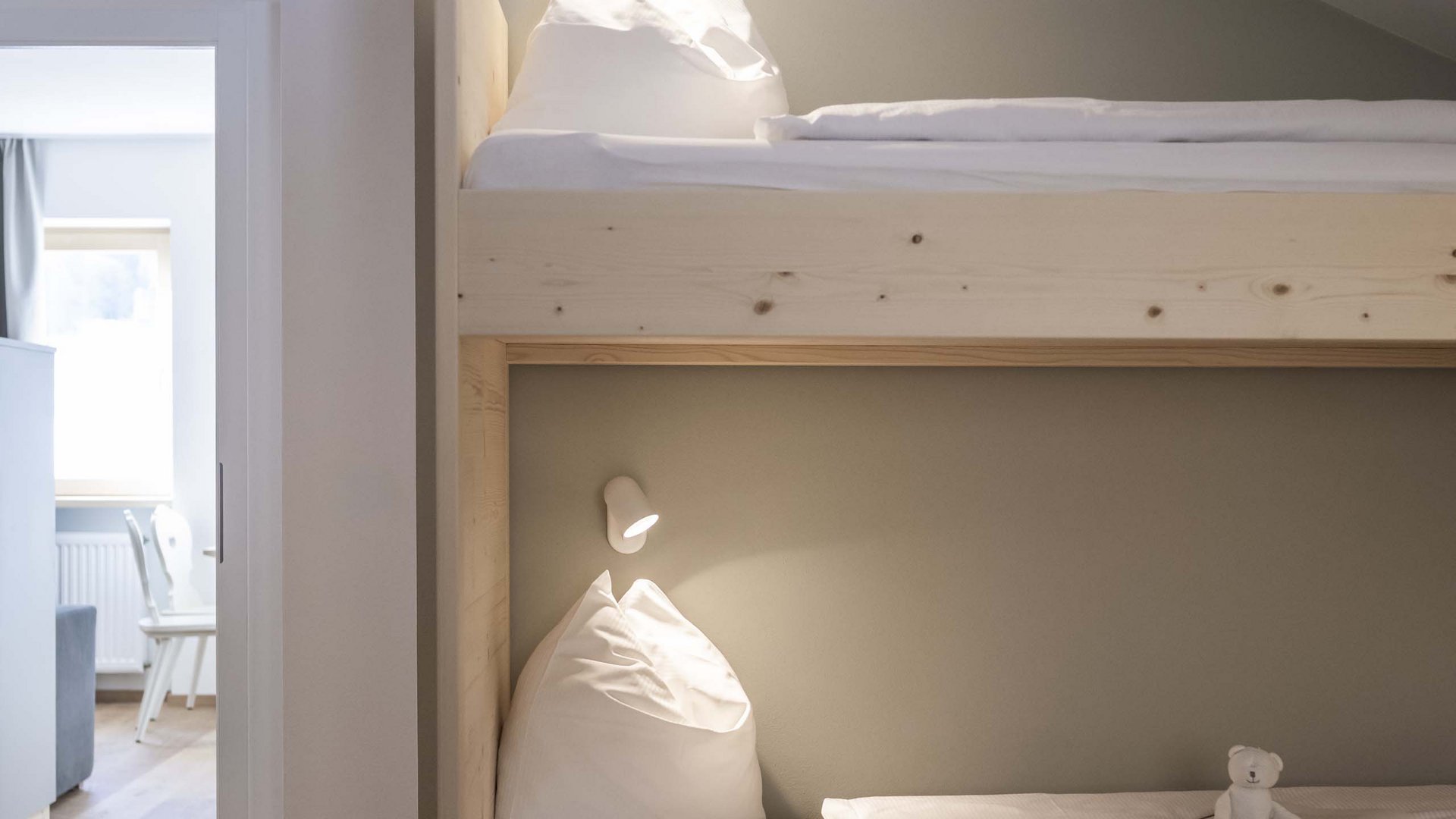 Residence Villa Rainer Letto a castello in legno chiaro con biancheria bianca e piccolo orsacchiotto