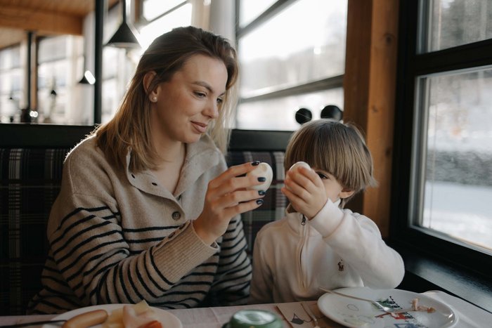 Puro divertimento al family hotel sulle piste da sci Donna e bambino che brindano con uova a colazione