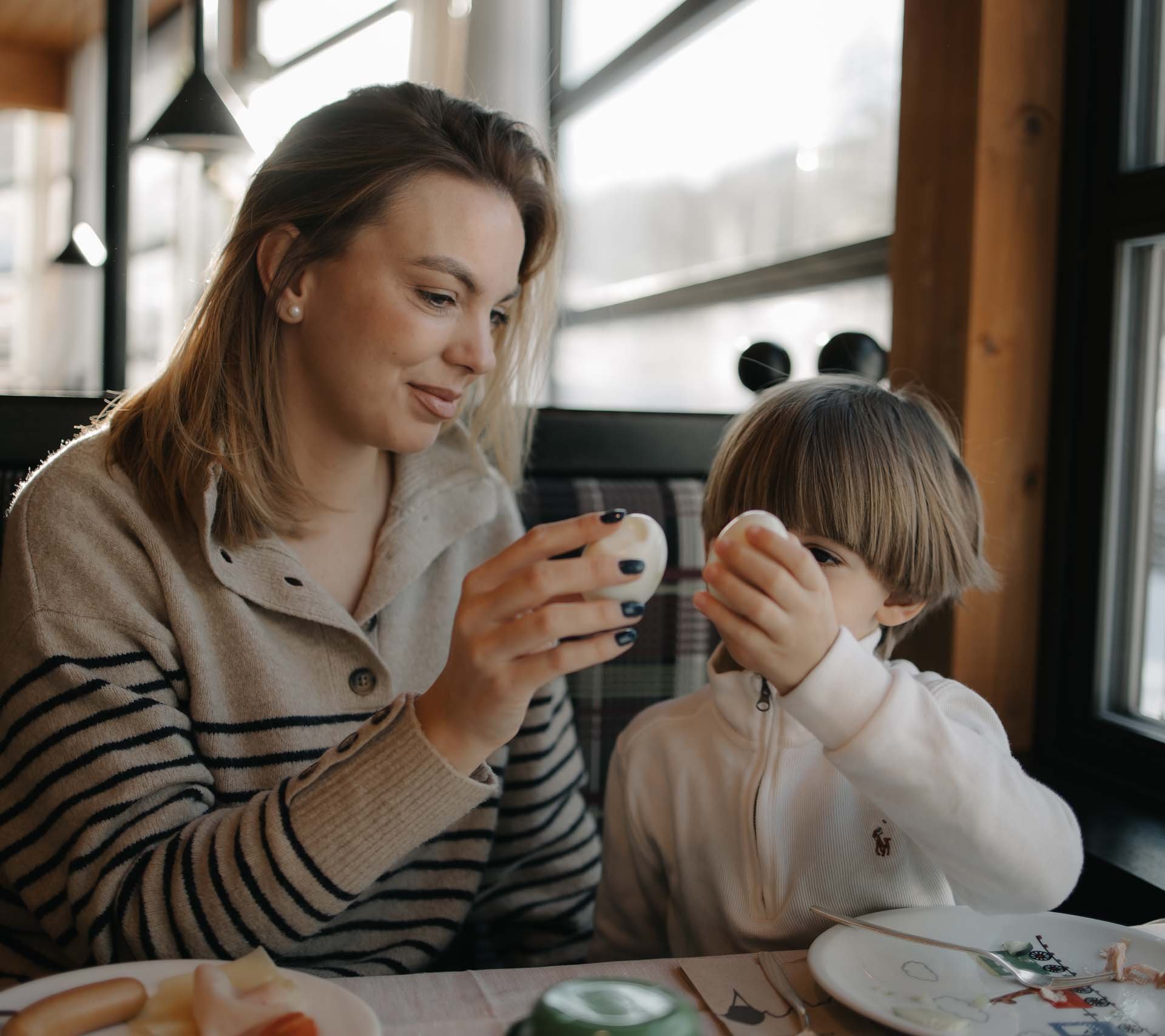 Property detail page - Hotel Rainer Woman and child clinking eggs at a breakfast table