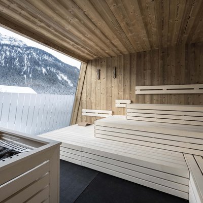 Ihr Familienresort in Südtirol Innensauna aus Holz mit Bergblick durch große Fensteröffnung