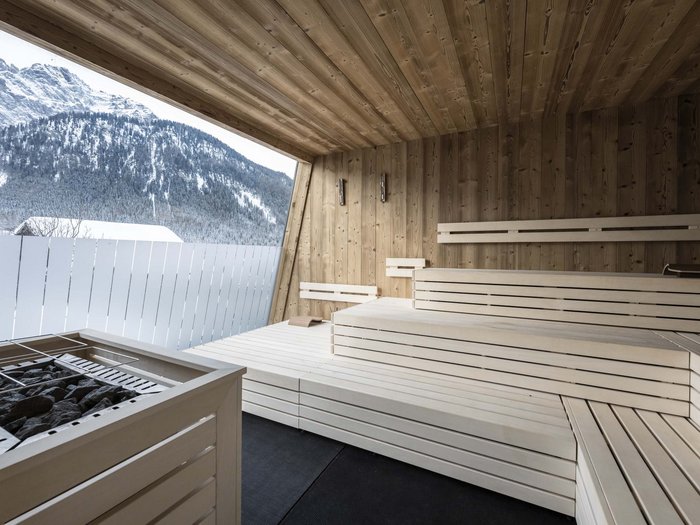 Relaxing wellness in the Dolomites: spa hotel in Sexten Wooden indoor sauna with mountain view through large window opening