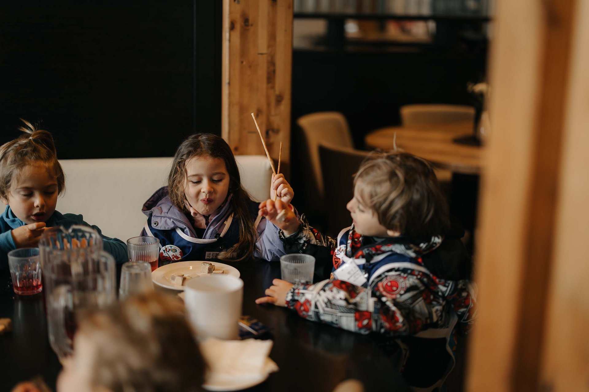 Ihr Familienresort in Südtirol Kinder essen gemeinsam und unterhalten sich am Esstisch