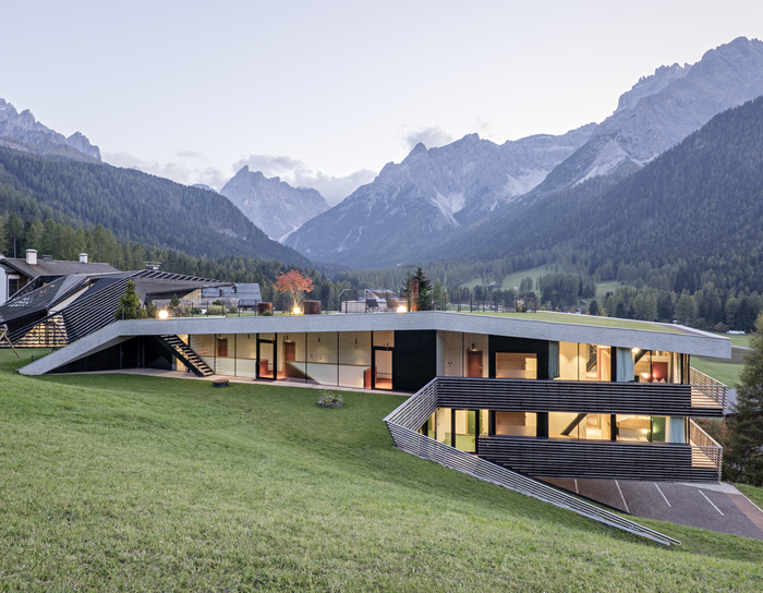 Modernes Haus mit großen Fenstern auf einem Hang mit Bergblick