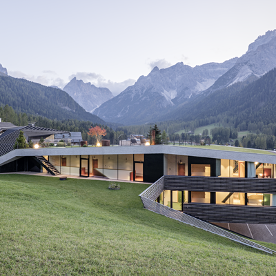 Modernes Haus mit großen Fenstern auf einem Hang mit Bergblick
