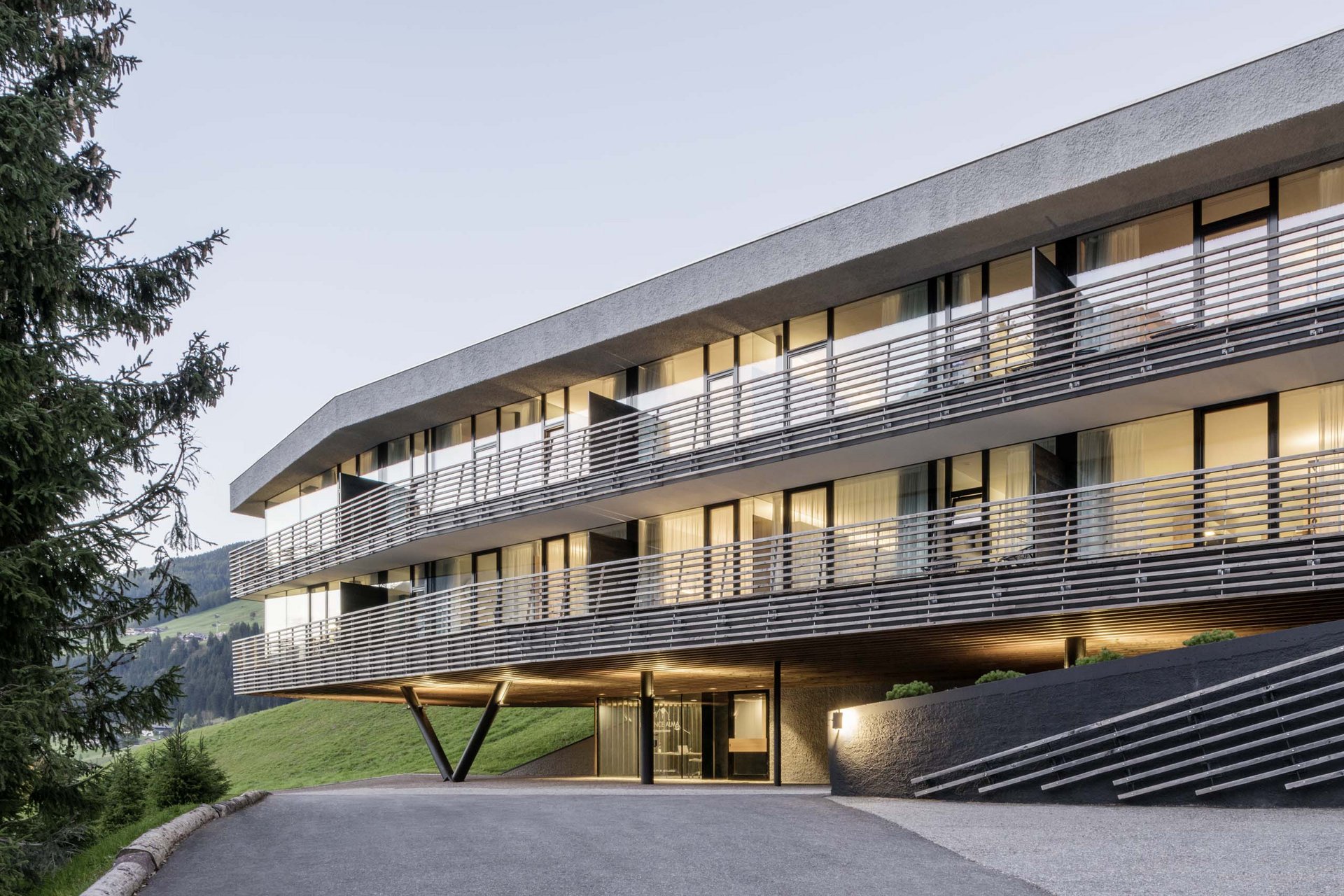 How to get to the Family Resort Rainer Modern hotel building in mountains with lit windows at dusk