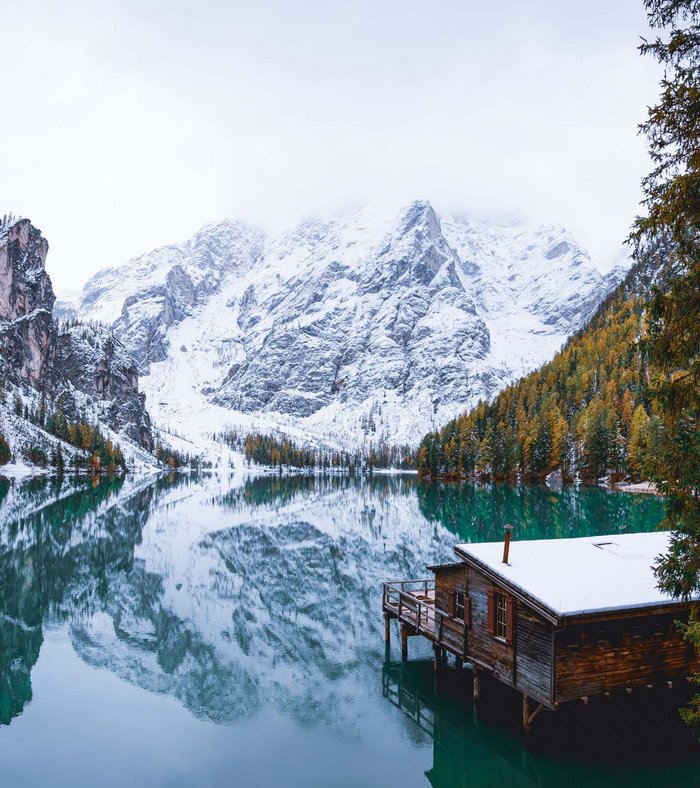 Sights around Sexten Wooden cabin on frozen lake with snow-covered mountains in the background