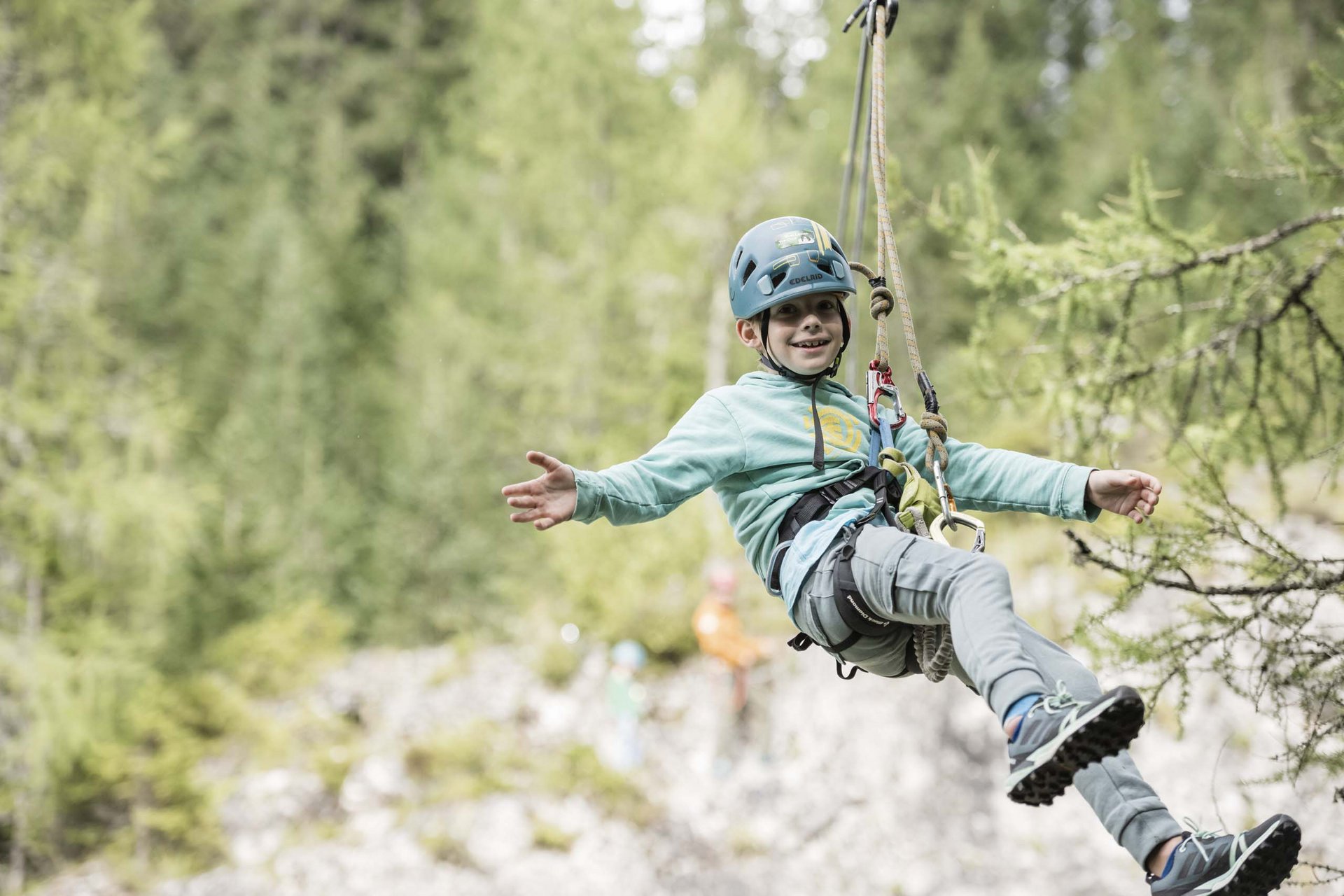 How to get to the Family Resort Rainer Happy boy wearing helmet climbing on rope in the forest