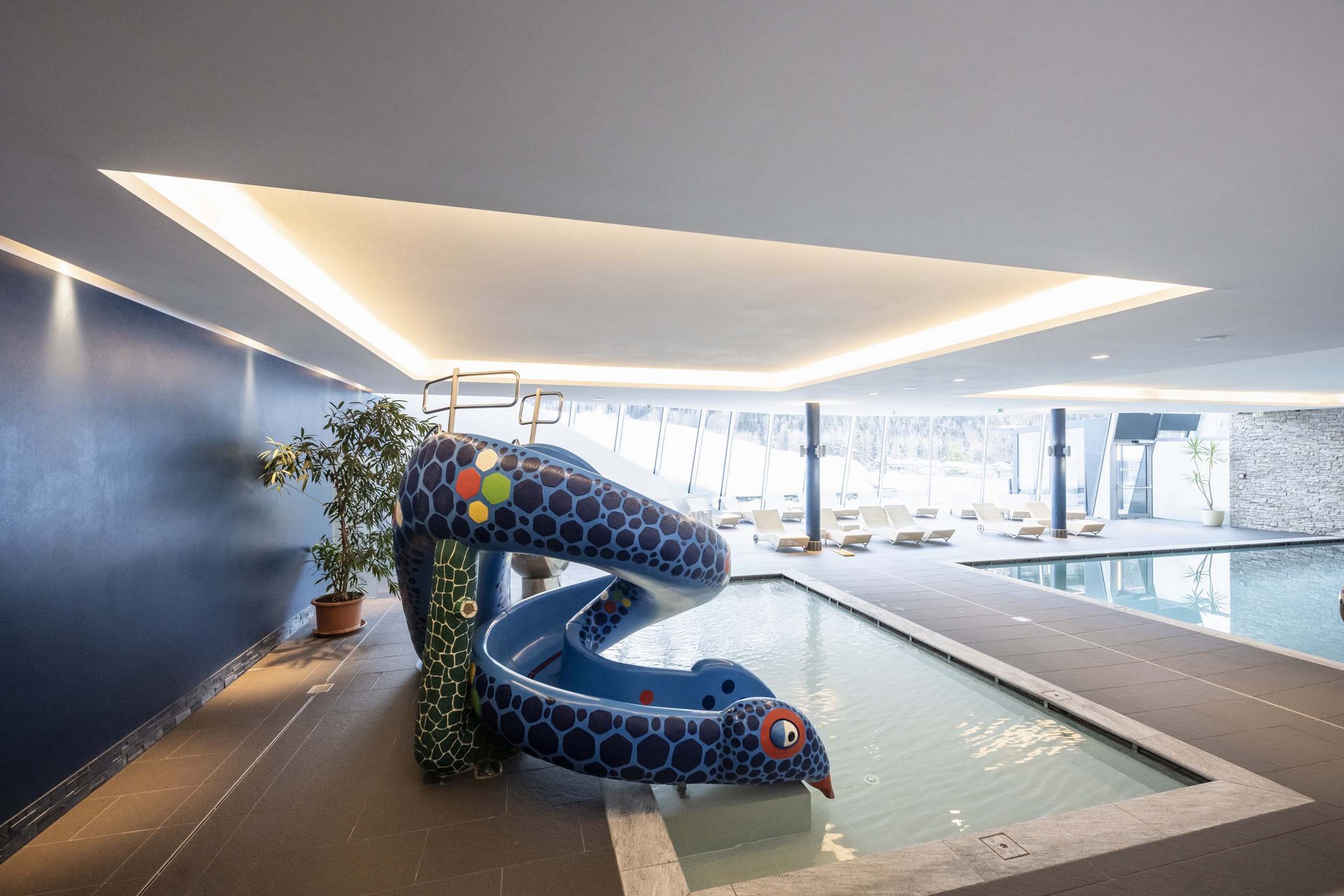 How to get to the Family Resort Rainer Indoor pool with colorful kids slide and lounge chairs in modern spa area