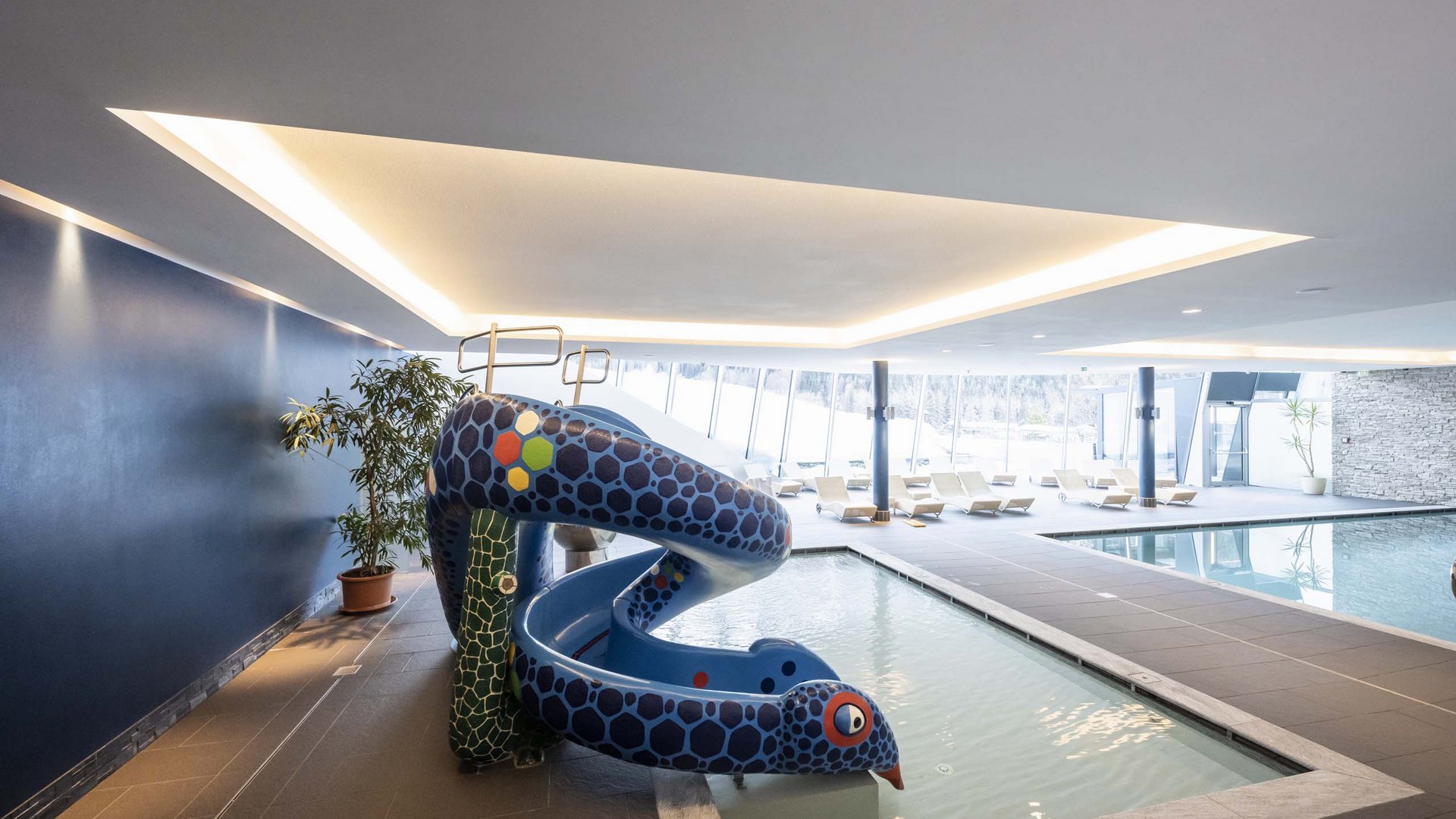 Family Resort Rainer Piscina interna con scivolo colorato per bambini e lettini in area spa moderna