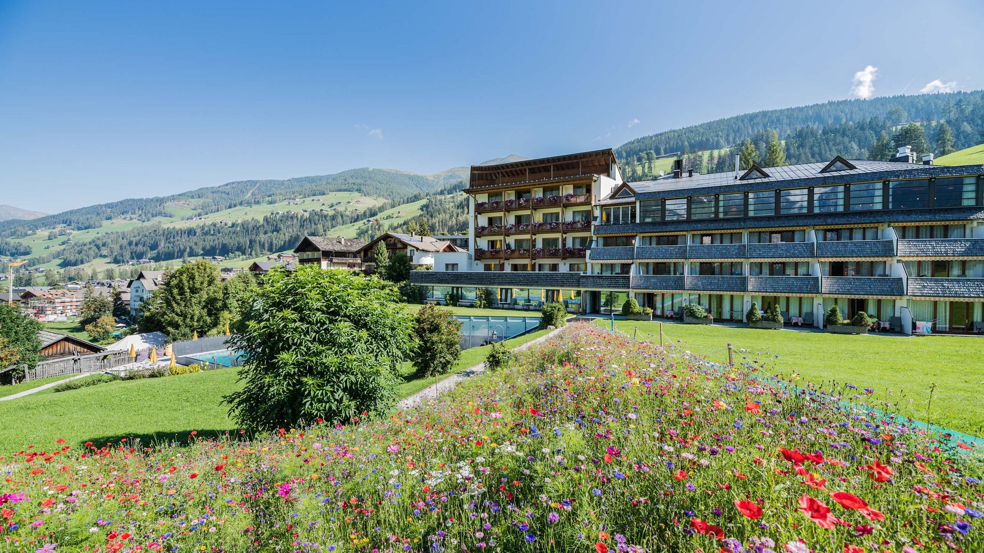 Family Resort Rainer Hotel con giardino fiorito e vista su montagne verdi sotto cielo sereno