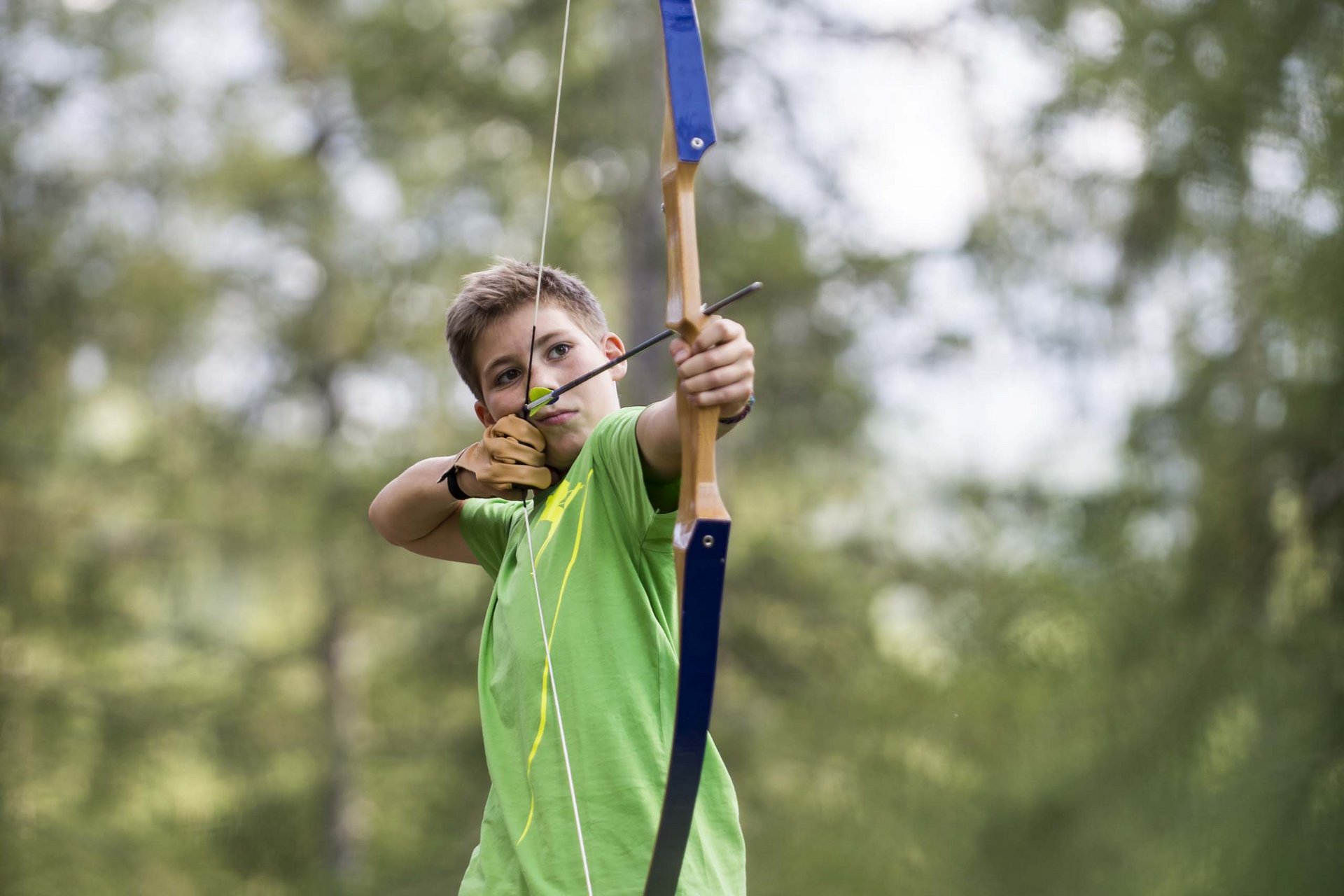 Ragazzo che spara con arco e freccia nella foresta