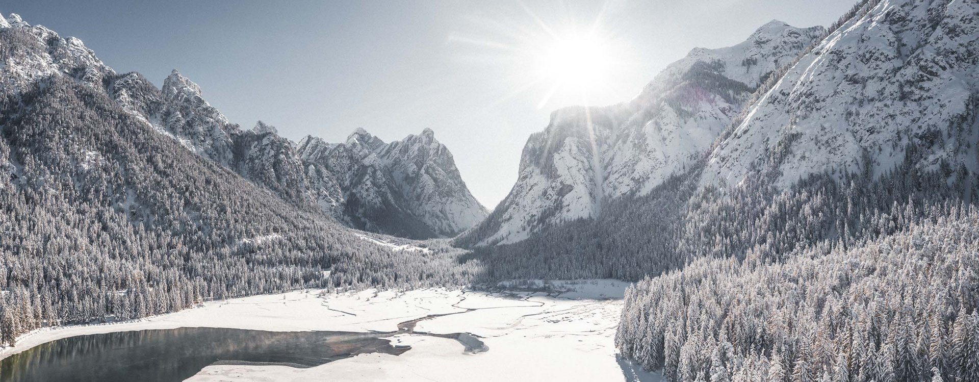 Winter sports away from the slopes Snow-covered mountain landscape with frozen lake and sunlight