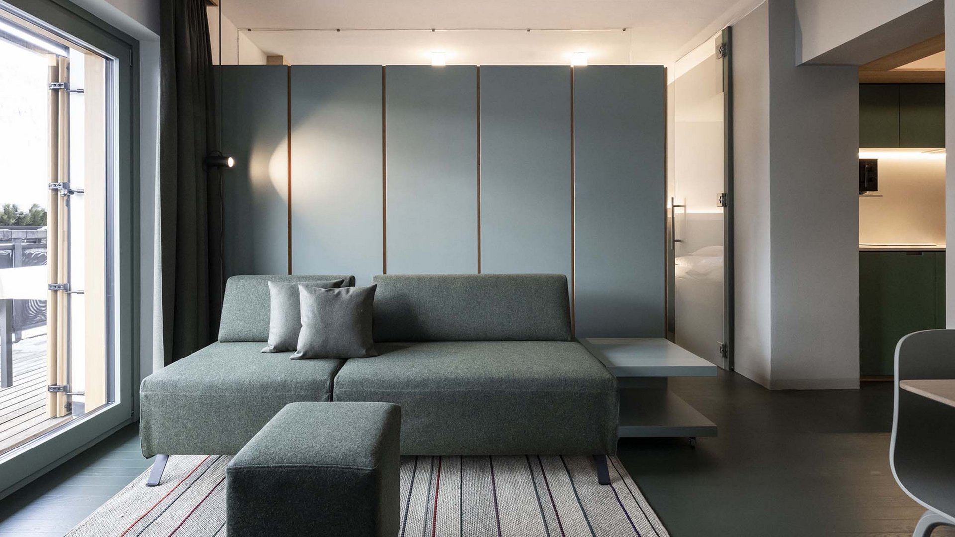 Residence Paramount Alma Soggiorno moderno con divano grigio, due cuscini e accesso al terrazzo