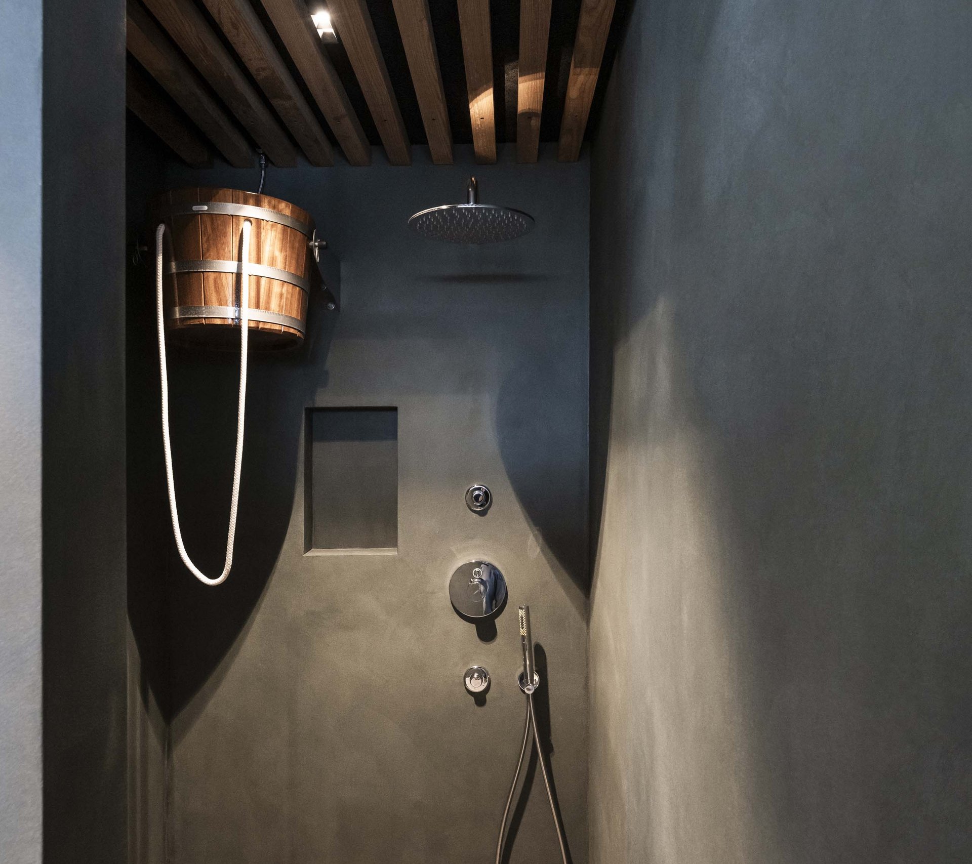 Moderne Duschanlage mit Holzeimer und Regendusche in dunklem Raum