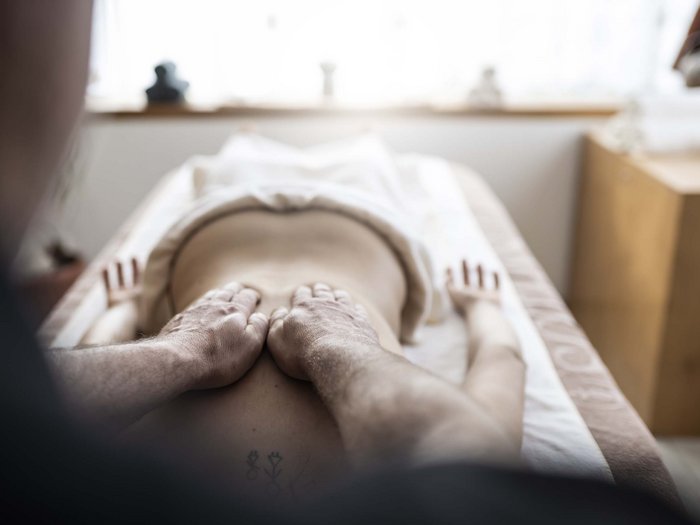Relaxing wellness in the Dolomites: spa hotel in Sexten Person lying on massage table receiving a back massage