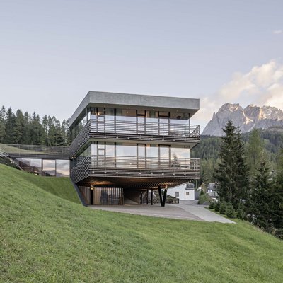 Ihr Familienresort in Südtirol Modernes Haus mit großen Fenstern auf einem Hang mit Bergblick