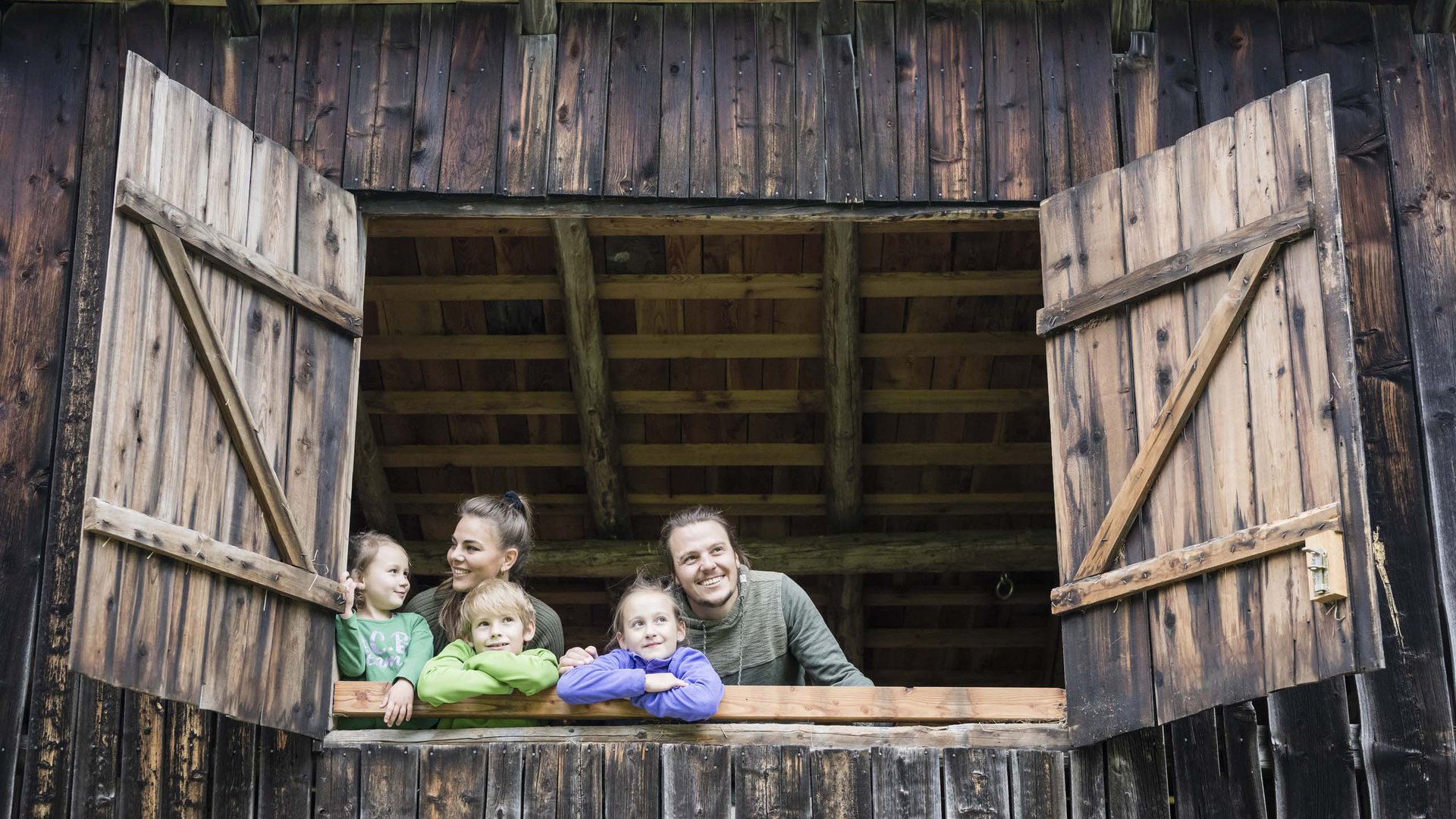 Qualche immagine del Rainer Famiglia guarda da finestra aperta di legno in un fienile rustico