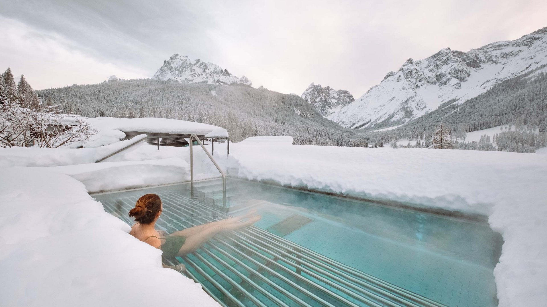 Residence Paramount Alma Donna si rilassa in piscina riscaldata all'aperto circondata da montagne innevate
