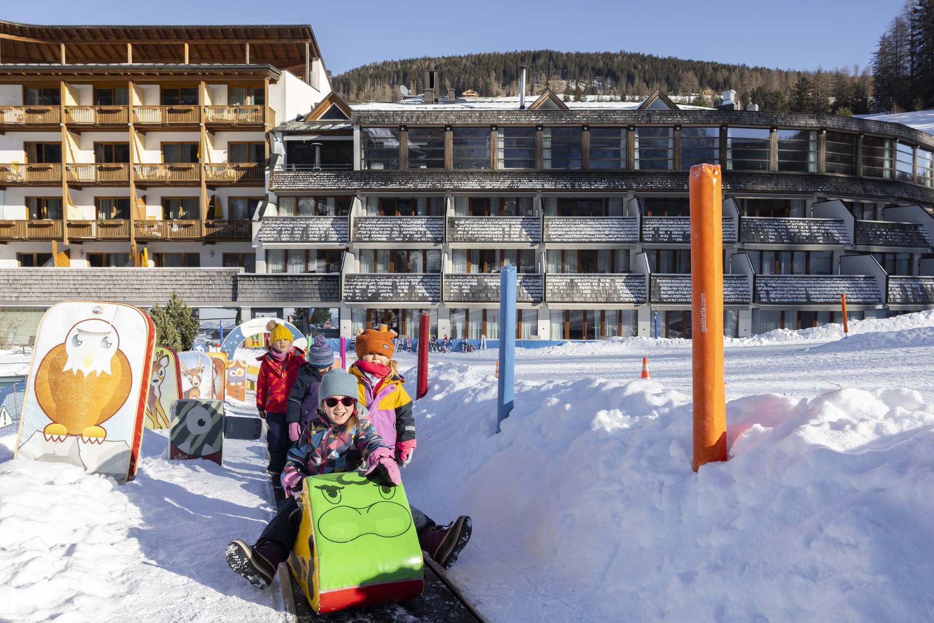 Bambini che slittano su un sentiero innevato davanti a un hotel d'inverno