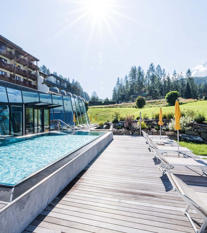 Ihr Familienresort in Südtirol Außenpool mit Liegestühlen und Sonnenschirmen bei sonnigem Himmel und grüner Landschaft