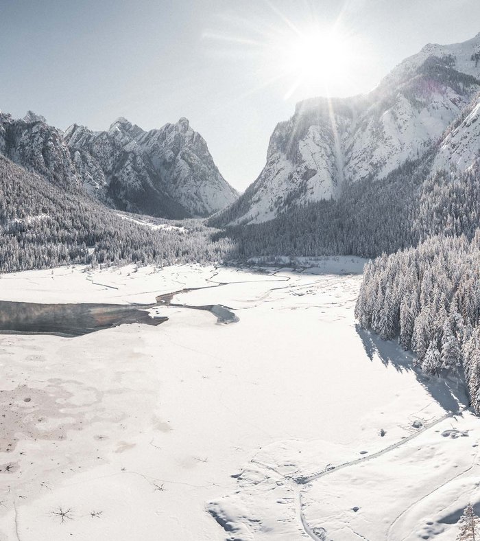Our family experiences Snow-covered mountains and forest with partially frozen lake in sunlight