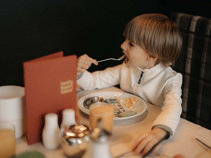 Gourmet delights from morning to night Child eating with a fork at a restaurant table
