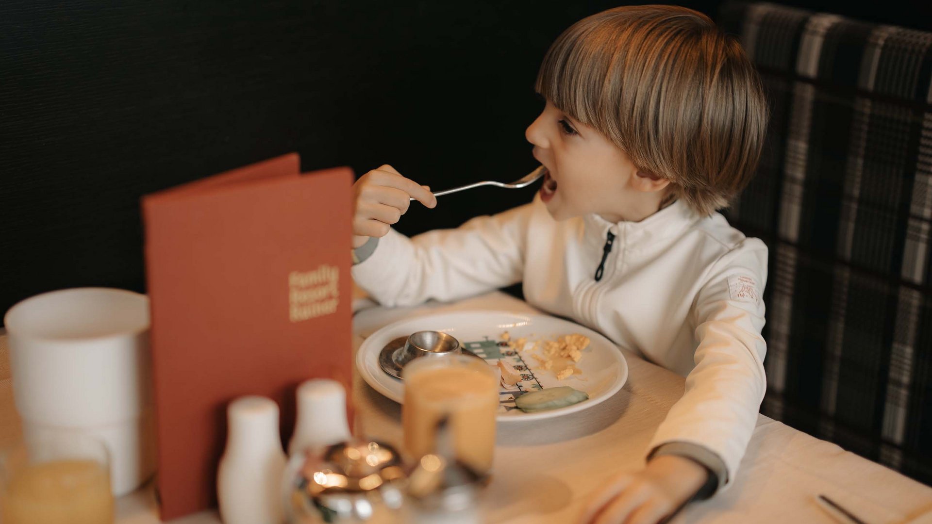 Family Resort Rainer Bambino che mangia con una forchetta al tavolo di un ristorante
