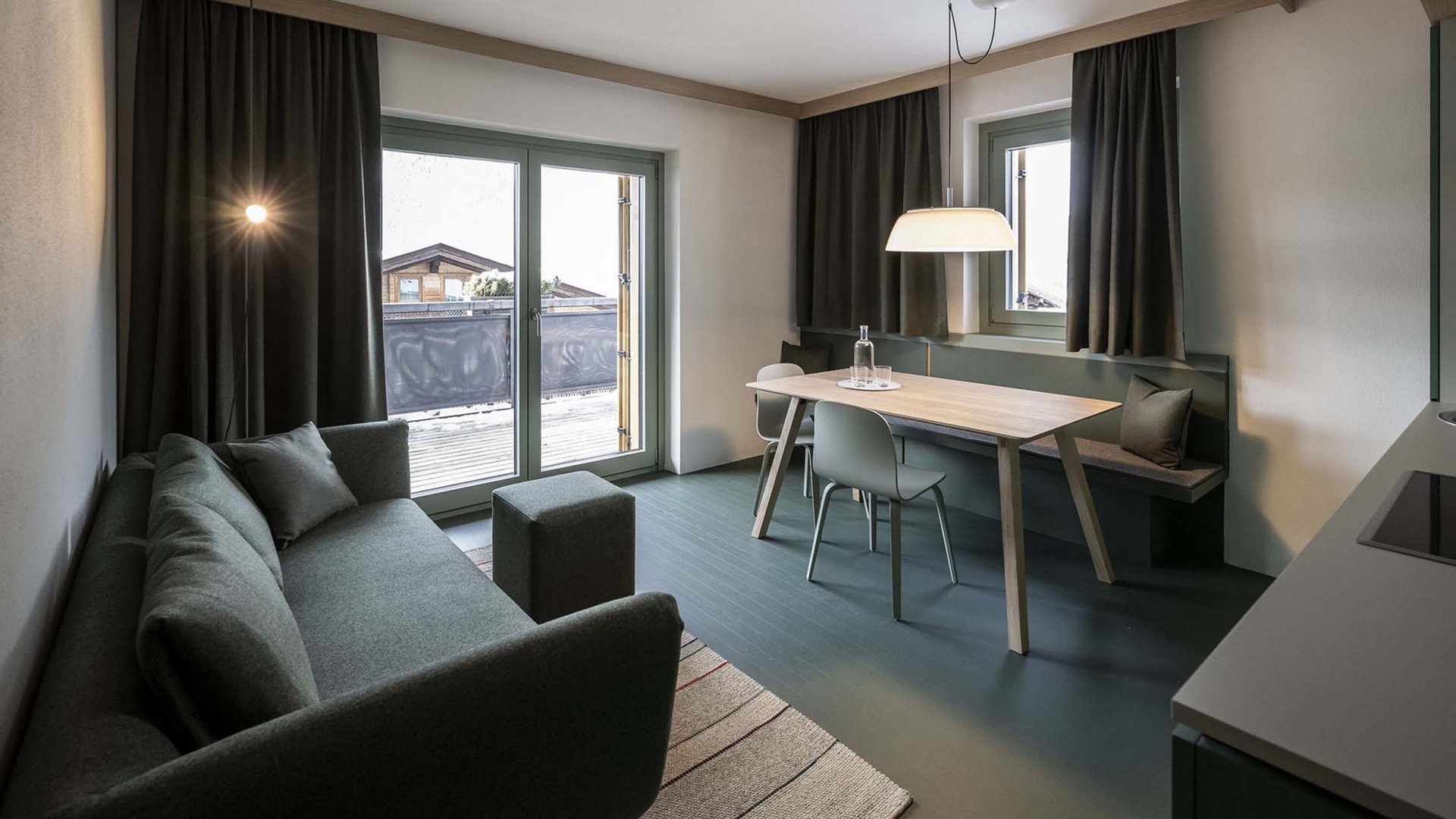 Residence Paramount Alma Soggiorno moderno con divano, tavolo da pranzo e balcone con vista montagna