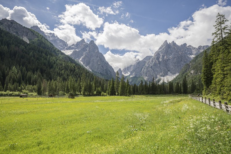 Rainer’s exclusive routes Green meadow with mountains and cloudy sky in the background