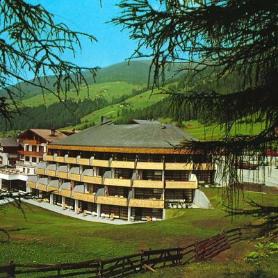 Edificio dell'hotel in una valle di montagna verde con alberi di pino