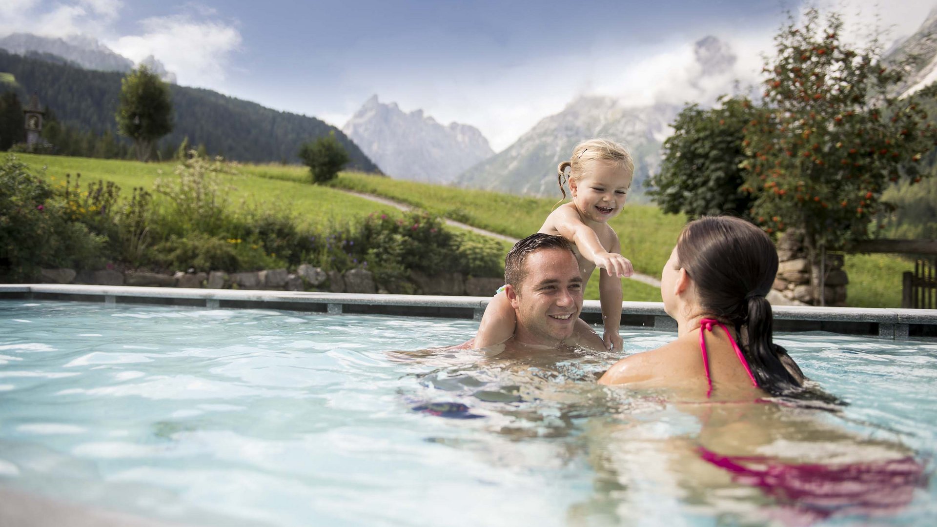 Family Resort Rainer Famiglia con bambino che gioca in piscina con montagne sullo sfondo