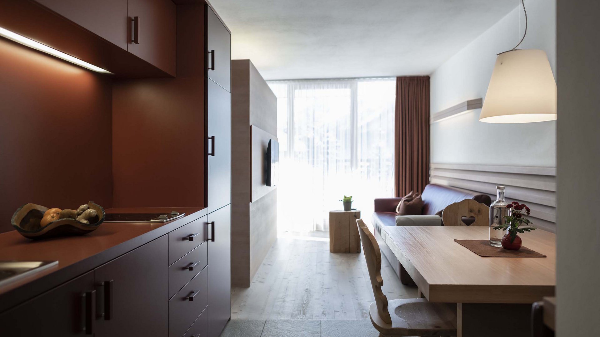 Residence Königswarte Strata Soggiorno moderno con angolo cottura, tavolo da pranzo e divano in colori caldi